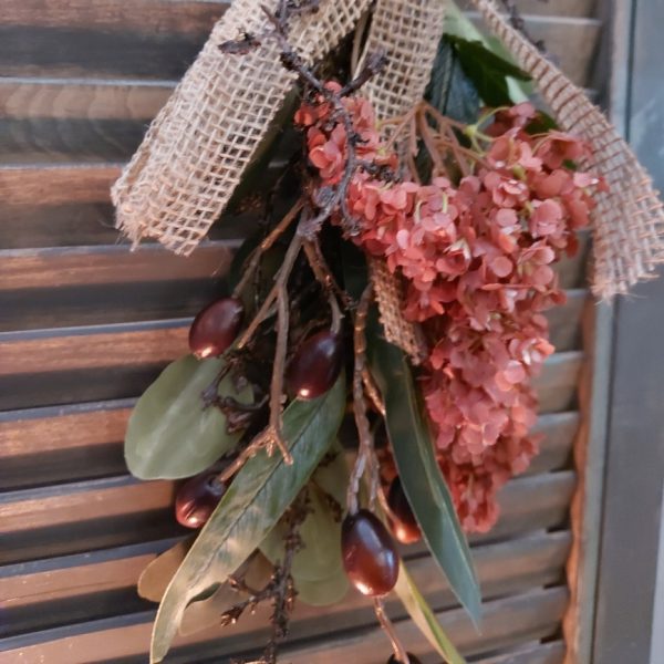 Toef van zijdenbloemen in warme winterkleuren, bij elkaar gebonden met jute koord en lint.