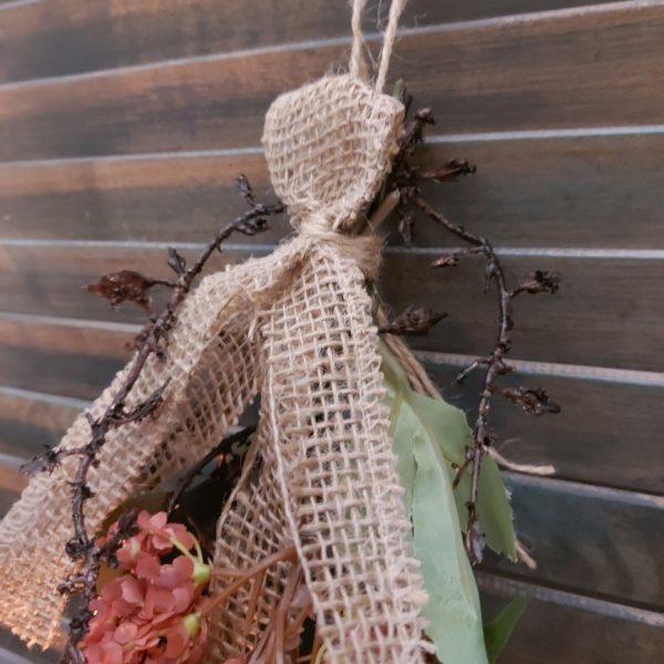 Toef van zijdenbloemen in warme winterkleuren, bij elkaar gebonden met jute koord en lint.