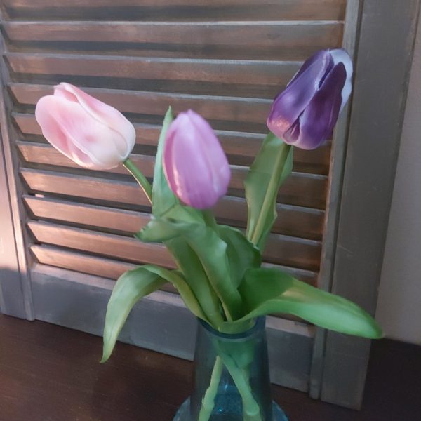 Glazen vaasje gevuld met drie kunsttulpen in lila kleurtinten.