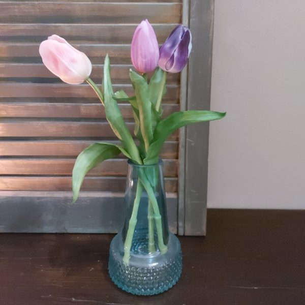 Glazen vaasje gevuld met drie kunsttulpen in lila kleurtinten.