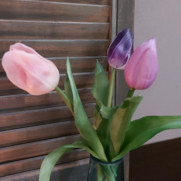 Glazen vaasje gevuld met drie kunsttulpen in lila kleurtinten.