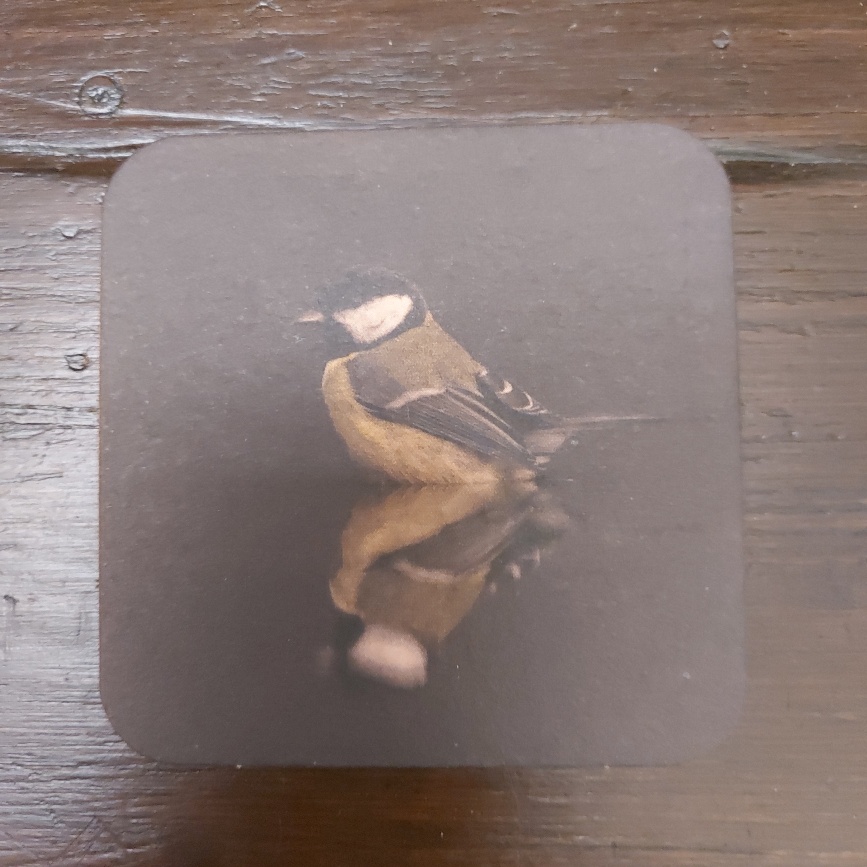 Onderzetter van viltkarton met de afbeelding van een koolmeesje. Dubbelzijdig bedrukt.