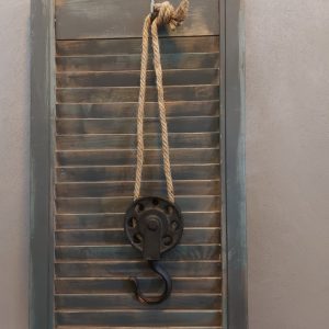 Decoratieve katrol ven metaal aan een jute koord.