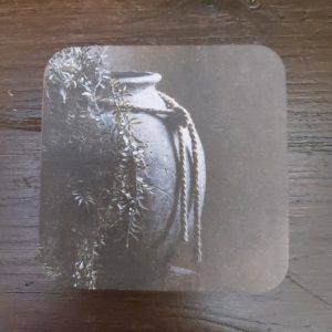 Onderzetter van viltkarton met de afbeelding van een kruik met plant. Dubbelzijdig bedrukt.